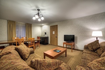 Comfortable couches, a TV, and a large dining table in a hotel room